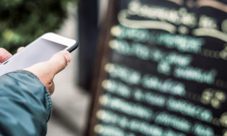 Mann, der vor einer Speisekarte Restaurantbewertungen auf Google oder Yelp liest.